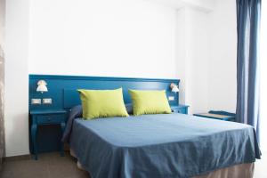 un letto blu con due cuscini gialli sopra di Isolotto Guest House a Porto Ercole