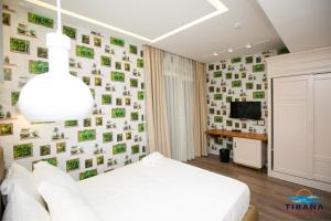 a bedroom with a white bed and a wall of pictures at Tirana Resort Radhime in Radhimë