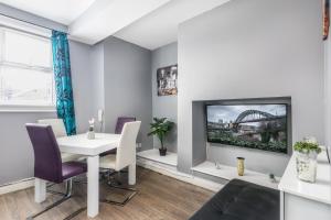 ein Esszimmer mit einem weißen Tisch und einem TV in der Unterkunft Sunderland City Centre Apartments free parking and Wi-Fi in Sunderland