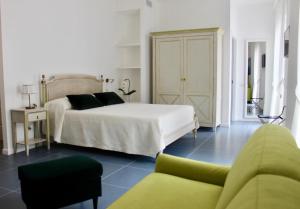 1 dormitorio con 1 cama blanca y 1 sofá verde en Cetara Costa d'Amalfi Residence, en Cetara