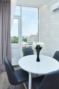 a white table with chairs and a vase of flowers on it at Panoramic Plaza Apartments in Odesa