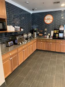 a kitchen with wooden cabinets and a tile wall at Howard Johnson by Wyndham Oklahoma City OKC Airport, Fairgrounds, I40 in Oklahoma City