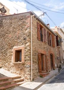 - un vieux bâtiment en pierre avec des portes et des fenêtres en bois dans l'établissement Maison 3ch 65m2 en bord de mer, à Banyuls-sur-Mer