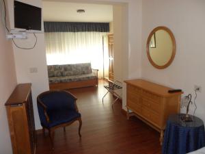 uma sala de estar com uma cadeira, uma cómoda e um espelho em Hotel Avenida em Sabaris