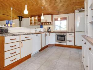 a large kitchen with white cabinets and a window at 6 person holiday home in Dannemare in Dannemare