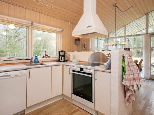cocina con armarios blancos, fregadero y fogones en 6 person holiday home in S by, en Saeby