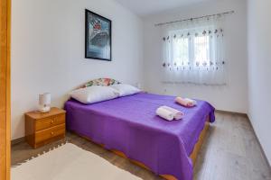 1 dormitorio con 1 cama morada y 2 toallas en Apartment A & J, en Petrčane
