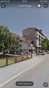 a street with a fence and cars on the road at Anton Apartment in Kočani