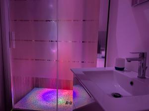 La salle de bains est pourvue d'un lavabo et d'une douche avec des lumières violettes. dans l'établissement Cutapp Guest House, à Catane