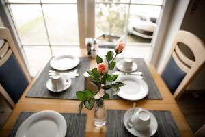 una mesa con platos blancos y un jarrón con flores. en Pension Frisia, en Norddeich