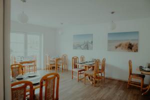 諾德代希的住宿－Pension Frisia，用餐室配有桌椅,墙上挂有绘画作品