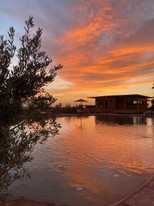 una puesta de sol sobre un cuerpo de agua con una casa en Le Parc des Oliviers, en Marrakech