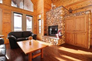 Cabaña de madera con sala de estar con chimenea de piedra. en Altitude Adjustment, en Duck Creek Village