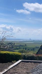 una vista de un campo desde una colina con una casa en LA BUTTE - Maison de vacances Avranches avec vue sur le Mont Saint Michel, en Le Val-Saint-Père