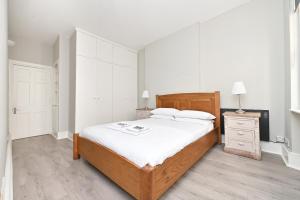 ein Schlafzimmer mit einem großen Bett und einer Kommode mit einem Nachttisch in der Unterkunft Soho Apartment, Piccadilly & Regent Street in London