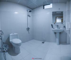 a white bathroom with a toilet and a sink at Hispar Hotel Skardu in Skardu