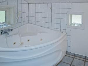 a white bath tub in a white tiled bathroom at 8 person holiday home in Nex in Vester Sømarken