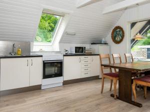 エーベルトフトにある6 person holiday home in Ebeltoftのキッチン(白いキャビネット、テーブル、椅子付)