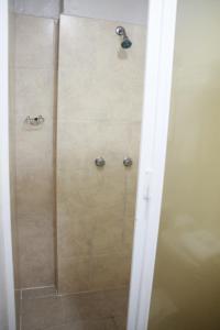 La salle de bains est pourvue d'une douche avec une porte en verre. dans l'établissement Casa de los Dulces Sueños, à Morelia