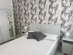a bedroom with a white bed with a bird wallpaper at Casa Palma in Paestum