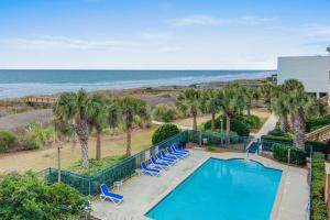 a pool with chairs and the ocean in the background at Seacabin Villa 230-B in Isle of Palms