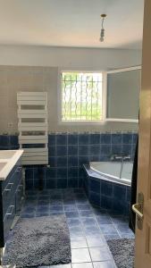 bagno piastrellato blu con vasca e finestra. di Villa en bordure de colline*piscine*clim*netflix a Les Matelles
