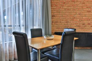 a wooden table with black chairs and a brick wall at Wonthaggi Motel in Wonthaggi