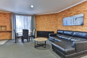 a living room with a leather couch and a table at Wonthaggi Motel in Wonthaggi