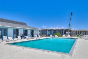 a swimming pool with lounge chairs and a building at Holiday Beach Dunes in Port Aransas