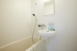 La salle de bains blanche est pourvue d'un lavabo et d'un miroir. dans l'établissement Designers Hotel Siesta, à Tokyo