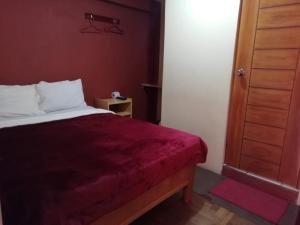 a bedroom with a bed with a red bedspread at Hostal Sumak'usi in Juliaca