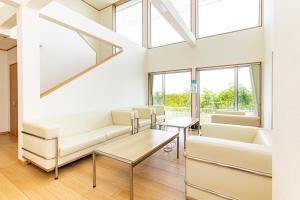 a living room with a couch and tables and windows at Tabist Hotel Takagiya Iwaki in Hisanohama