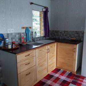 uma cozinha com armários de madeira, um lavatório e uma janela em Raihei Location maison d'hôtes em Bora Bora