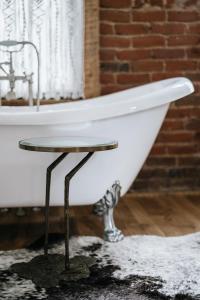 a white bath tub with a table next to a brick wall at The Inn in Buena Vista