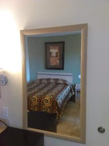 espejo reflejo de una cama en un dormitorio en RED CARPET INN LOUISVILLE NORTH -Jeffersonville In en Jeffersonville