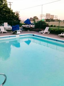 Una gran piscina azul con sillas y una mesa. en RED CARPET INN LOUISVILLE NORTH -Jeffersonville In en Jeffersonville