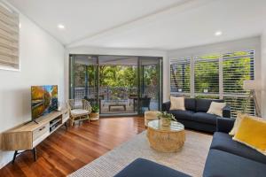 un soggiorno con un divano blu e una TV di Castaway Cove Beachfront Home by Stay Noosa a Marcus Beach