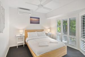 una camera da letto bianca con un letto e due finestre di Castaway Cove Beachfront Home by Stay Noosa a Marcus Beach Altre 10 foto