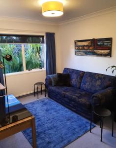 een woonkamer met een blauwe bank en een raam bij Central Oasis in Tauranga