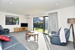 uma sala de estar com um sofá, uma mesa e uma televisão em Lavandula 3 - Christchurch Holiday Homes em Christchurch