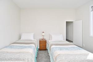two beds in a room with white walls at Lavandula 3 - Christchurch Holiday Homes in Christchurch