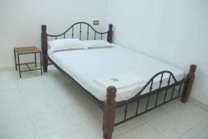 a bed with a wooden frame and white sheets at East Coast in Trivandrum