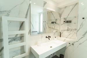 W białej łazience znajduje się umywalka i lustro. w obiekcie B&B Nel Blu Dipinto Di Blu w mieście Polignano a Mare
