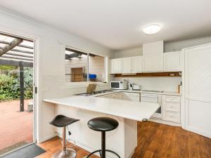 a kitchen with white cabinets and a counter and stools at Sunset Strip 4 in Torquay