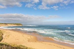 a sandy beach with the ocean on a cloudy day at Wonthaggi Motel in Wonthaggi