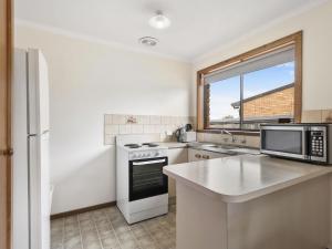 a kitchen with a stove and a microwave at Muirfield Beach Unit 1-23 in Torquay