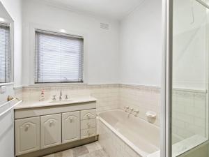 a white bathroom with a tub and a sink at Francis Geelong 156 in Belmont
