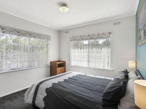 a bedroom with a large bed and two windows at Coffey Court Cottage 2 in Torquay