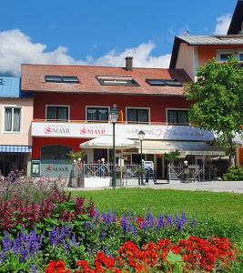 un edificio rojo con flores delante en Appartements MAYR inklusive ganzjährig GRATIS Zugang zur ALPENTHERME und im SOMMER kostenlose Bergbahnnutzung, en Bad Hofgastein