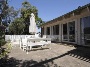 a white bench and an umbrella next to a house at Barnett Place 6 in Torquay +1 photo